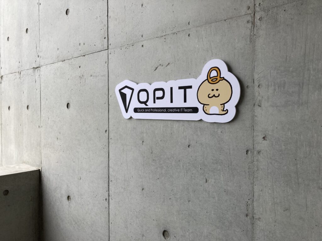 QPITのロゴとキャラクターがある壁面